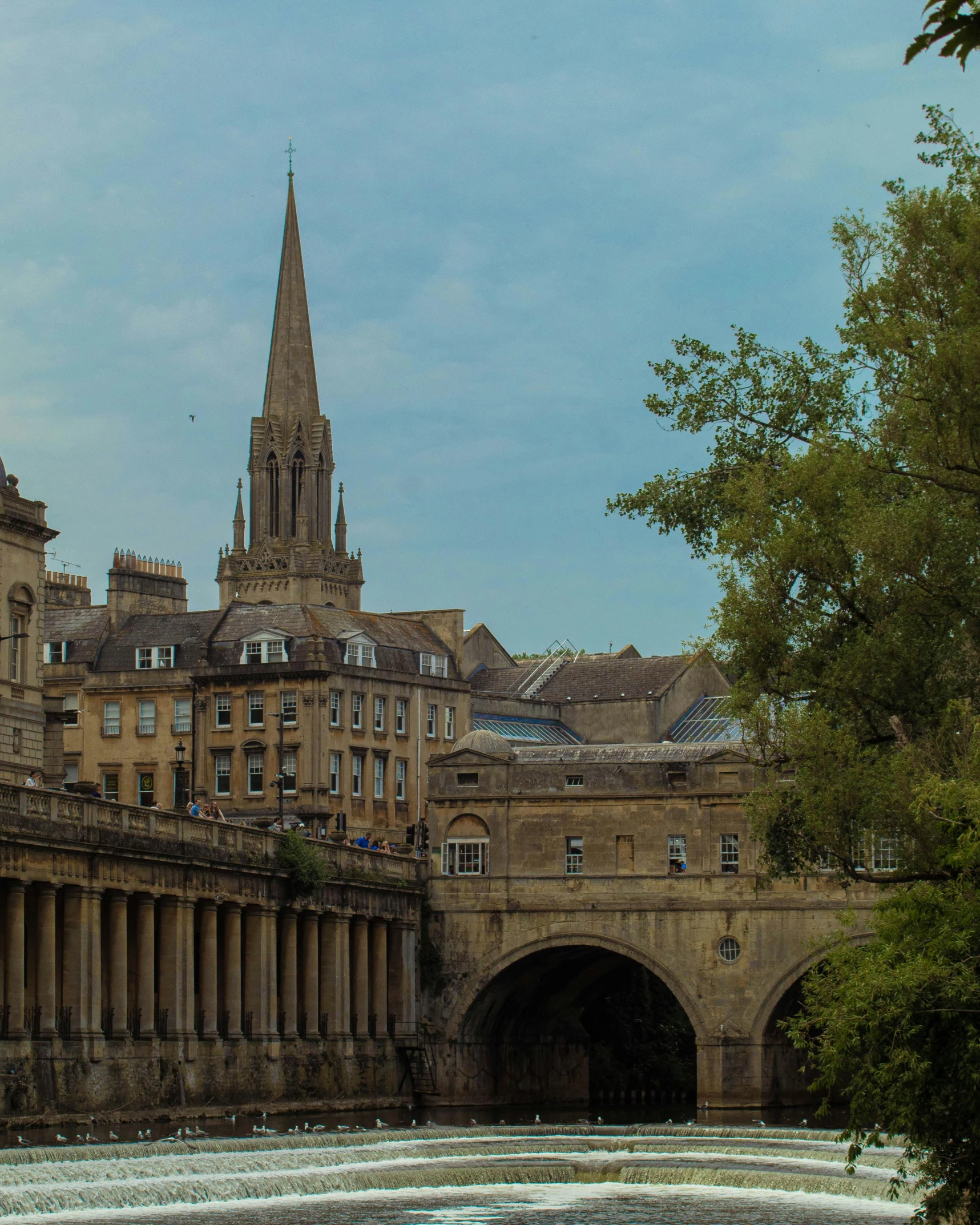 an old cathedral rises above buildings beside a small river