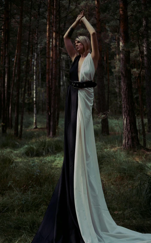 a woman in black and white dress standing near trees