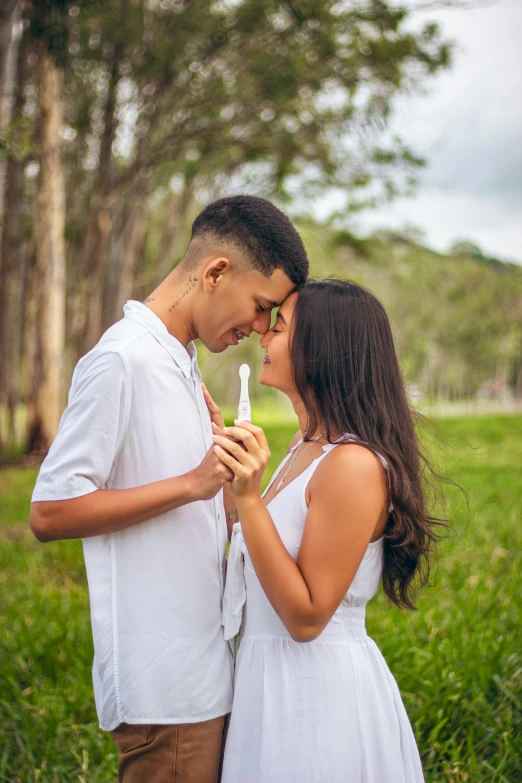 a couple poses for the camera while holding a small bottle