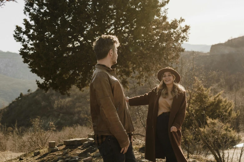 the couple stands on top of the hill, and holds hands