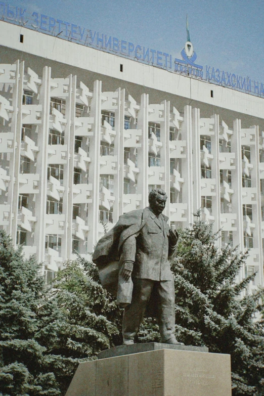 a statue in front of a white building with trees around it