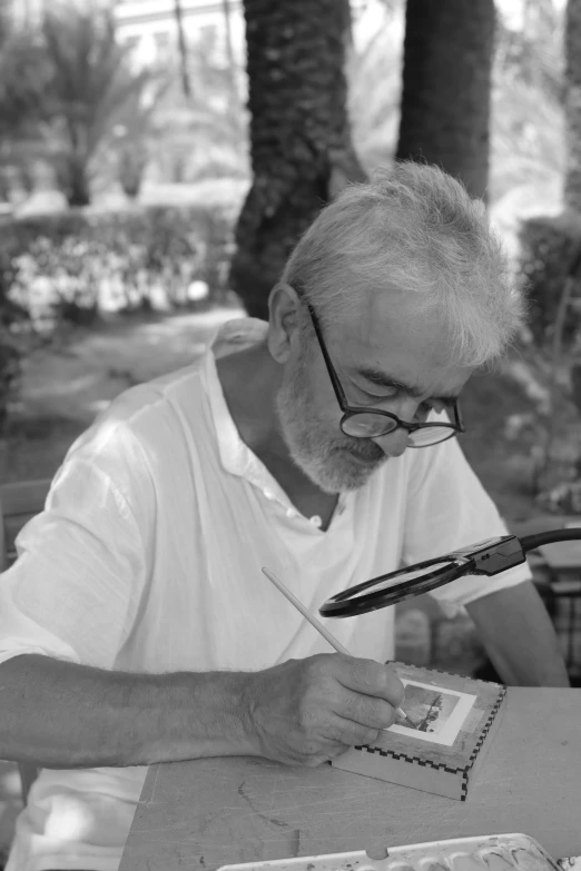 a man in white shirt painting outside with brush