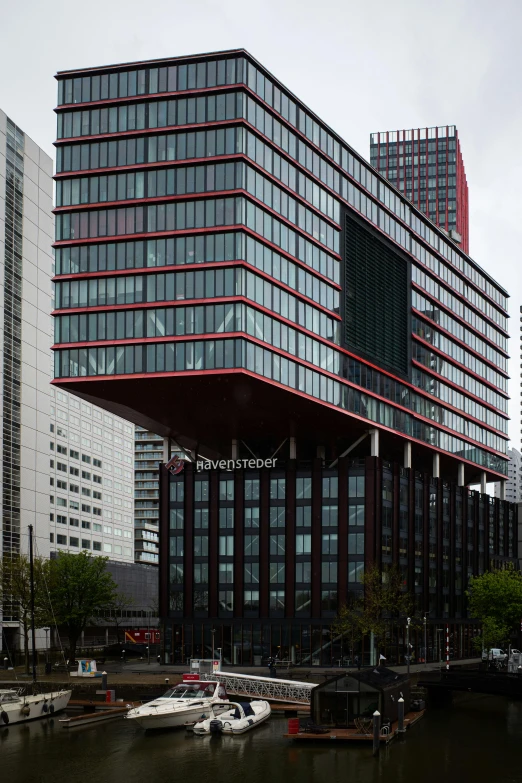 a large building with a lot of windows and a sail boat floating on the water