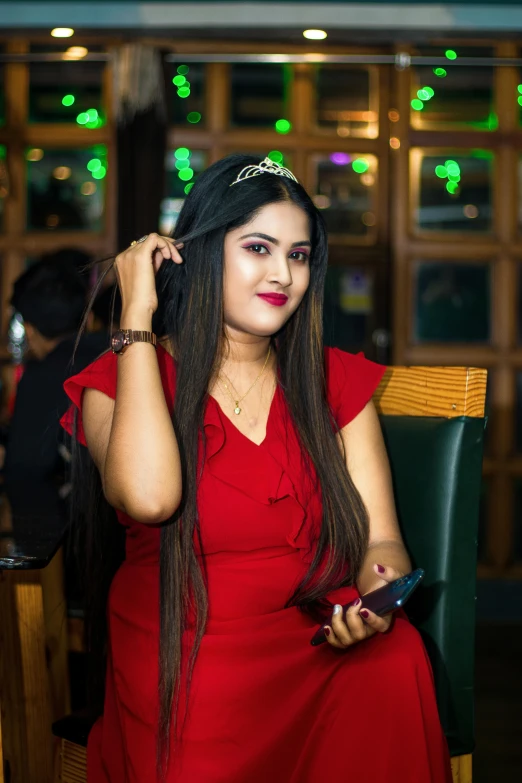 a girl in a red dress sitting on a chair