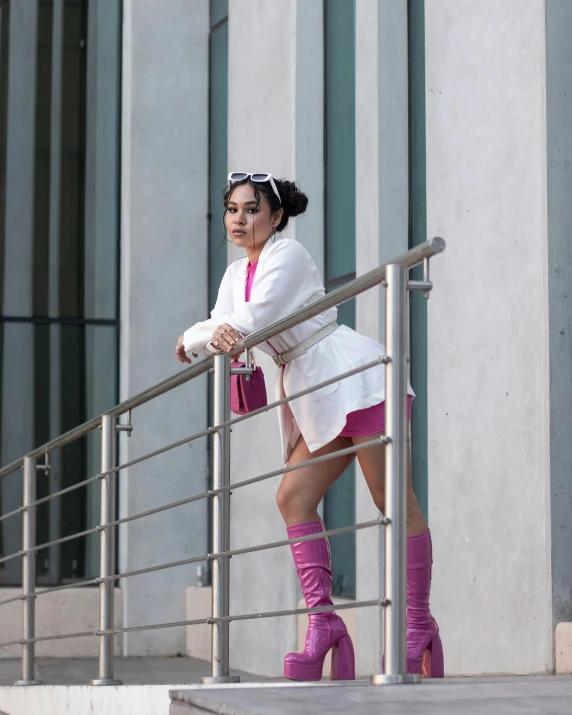 woman with pink shoes leaning on railing wearing purple boots