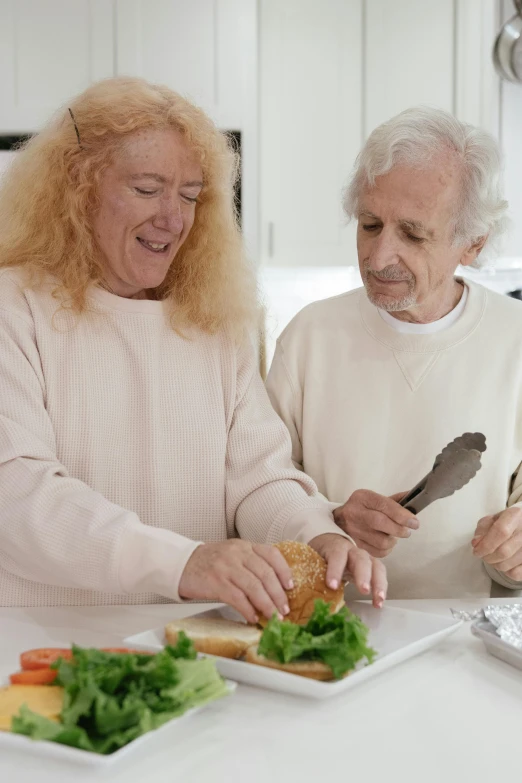 the older couple are enjoying their sandwich in the kitchen