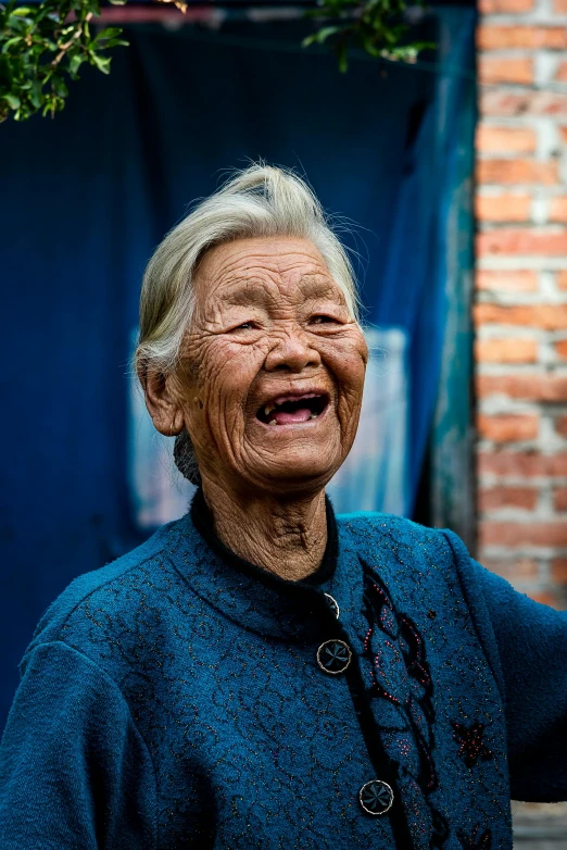 an old woman smiling in front of a wall