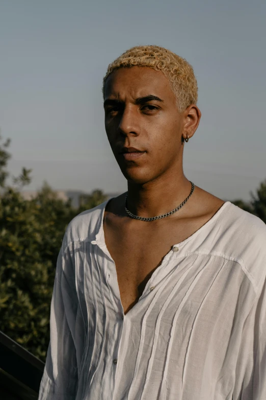 a black man in white shirt with necklace on