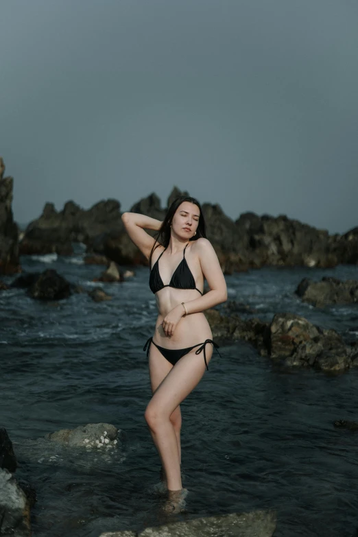 a woman in a black bikini is standing in the water