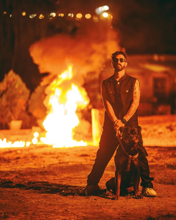 a man stands by a fire while holding a dog