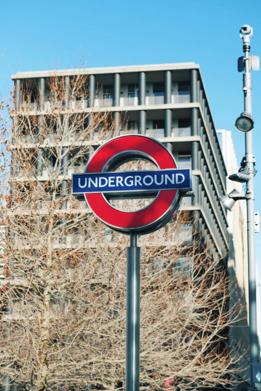 a red bus that is underneath a blue sign