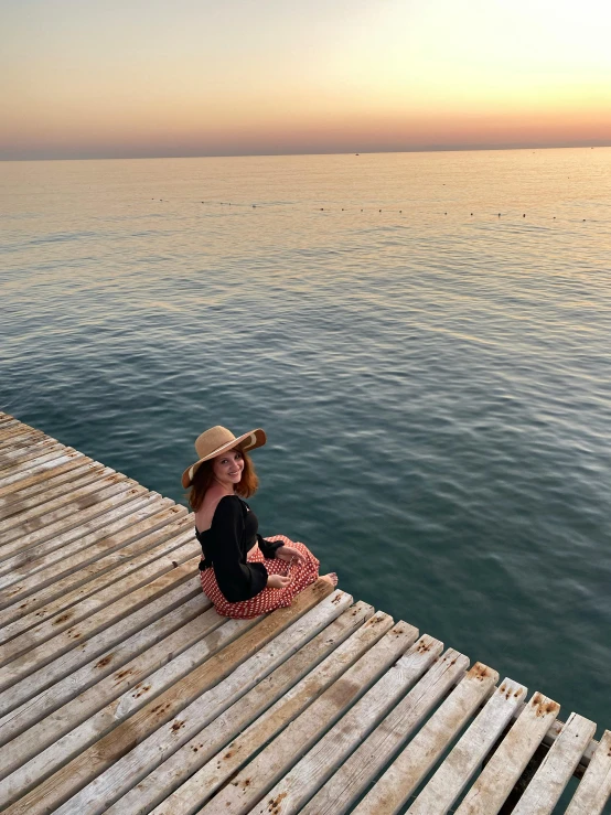 a little girl sits on a dock with water