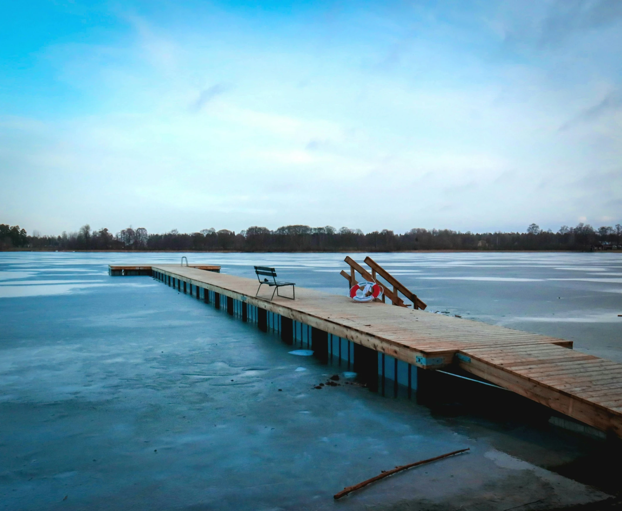 two benches are on the long dock with snowy water