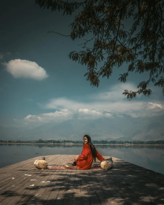 woman sitting in the middle of a dock with a body of water