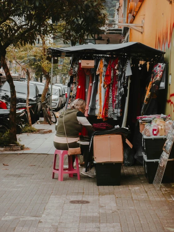 a person sits at an outside market looking at soing