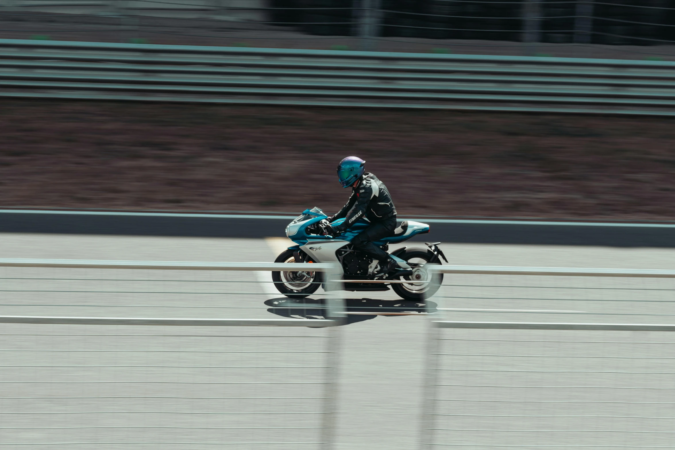 man wearing full body black and blue racing gear riding on a white motorbike