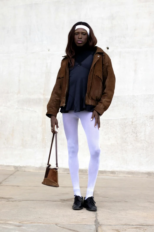 a person standing with a handbag near a wall