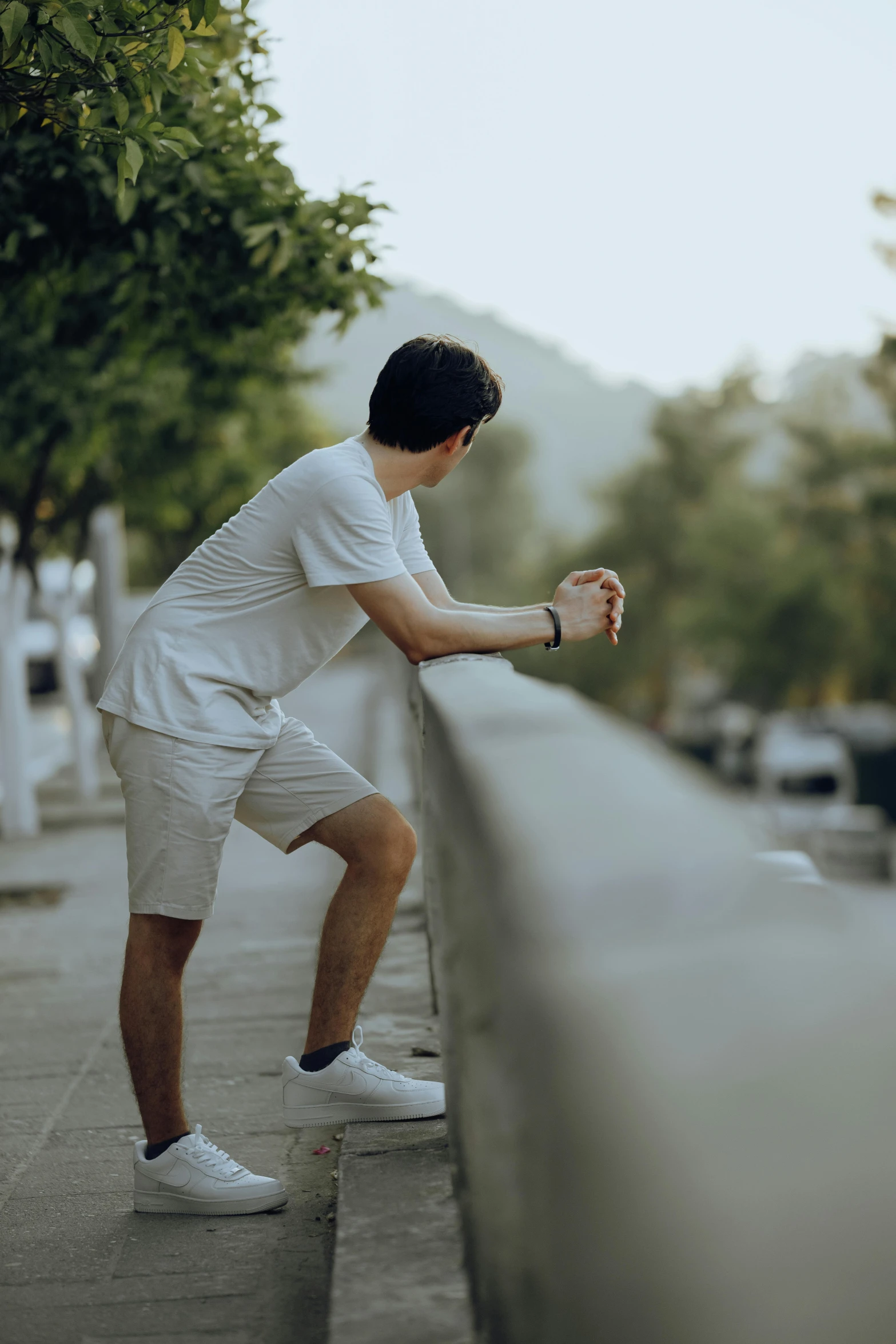 a young man is standing near a wall and holding onto the railing