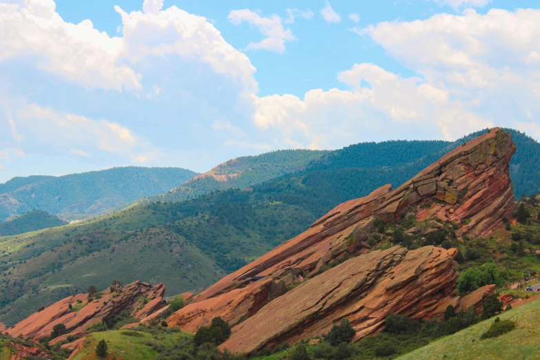 mountains rise above a green hillside under blue skies