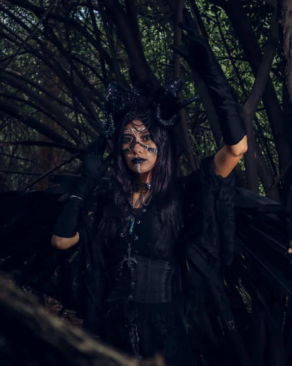 a girl with dark makeup and horns and make - up in a forest