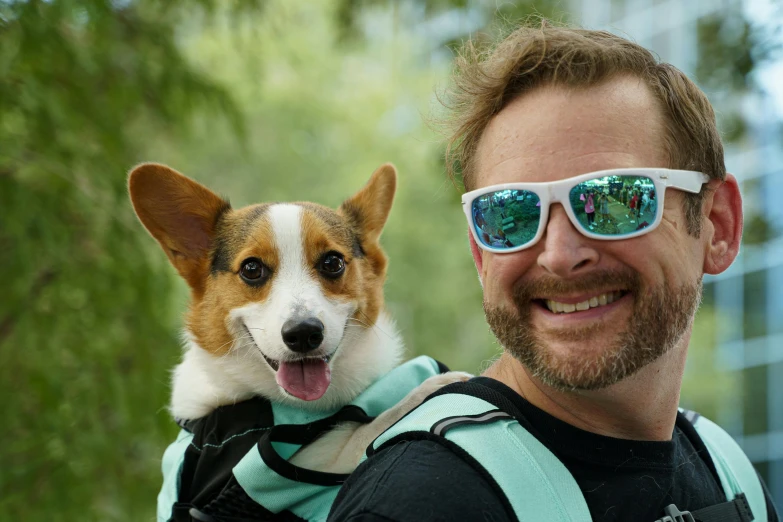 the man is smiling while his dog gets some shade