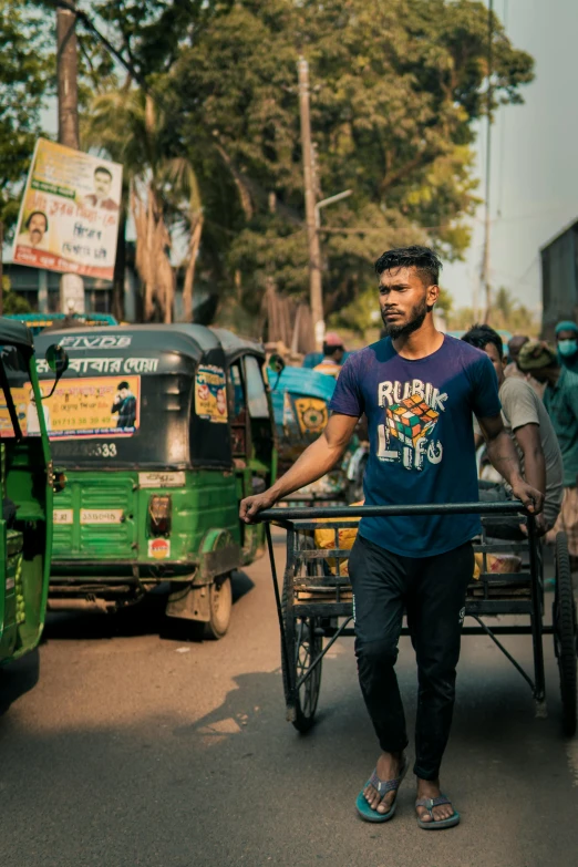 a man pulling a wheelbarrow with several carts on the side of the road