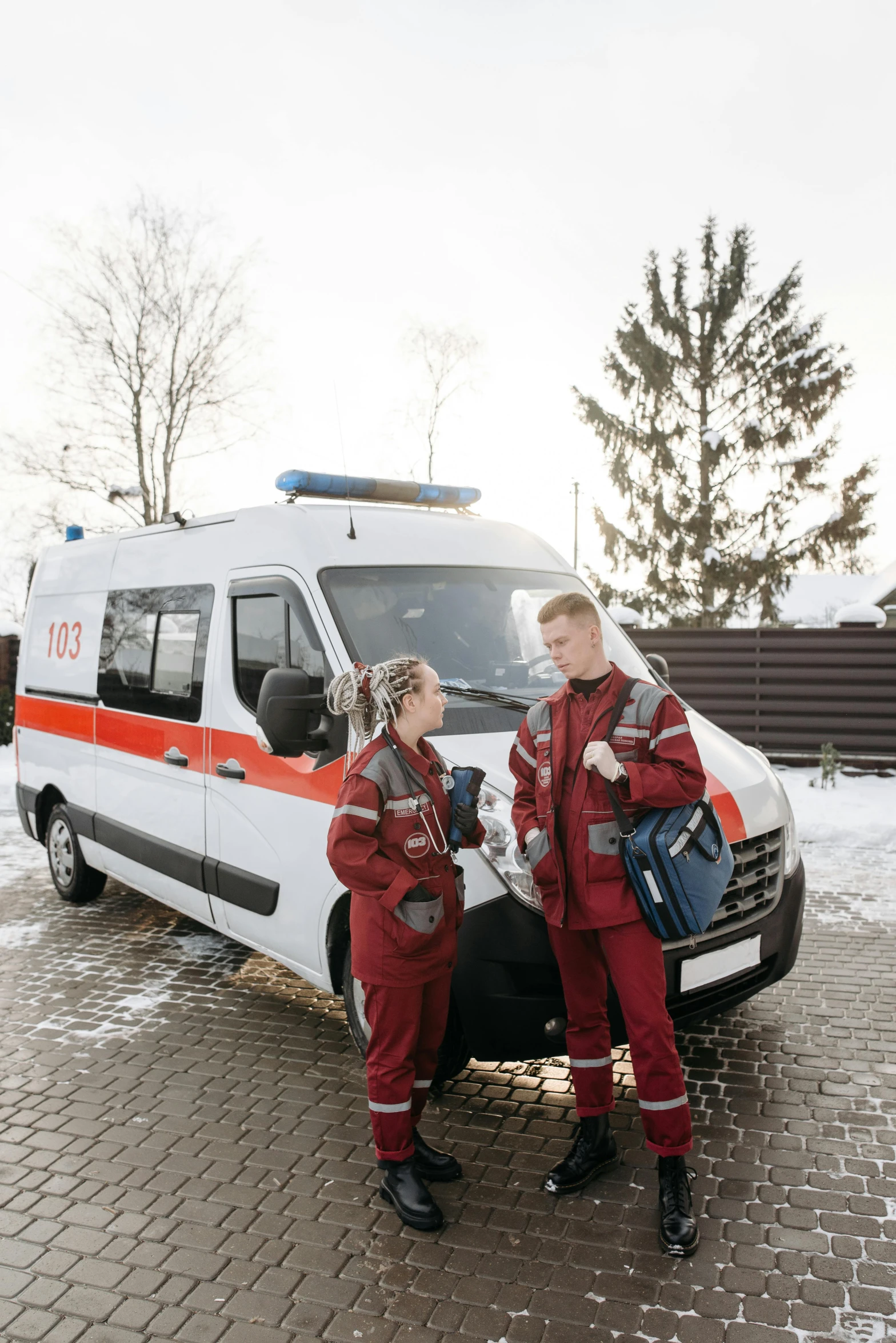 two young people are in front of an ambulance