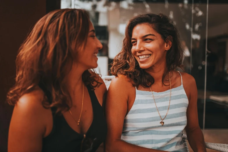 two beautiful women sitting on top of a bench