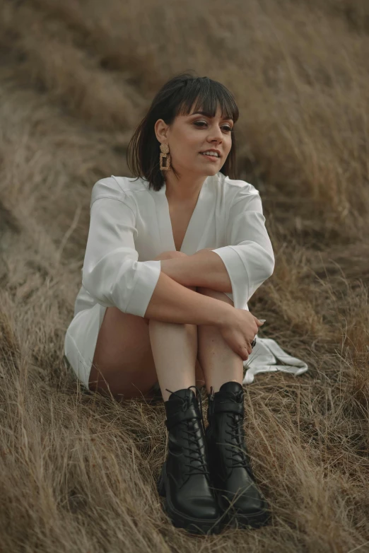 a woman is sitting on the ground in the field