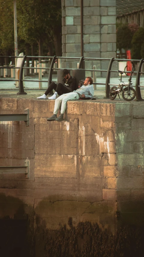 two men sleeping on the side of a wall