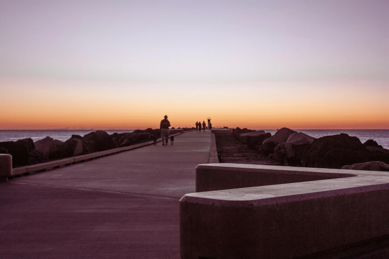 the sun is rising over the beach by the ocean