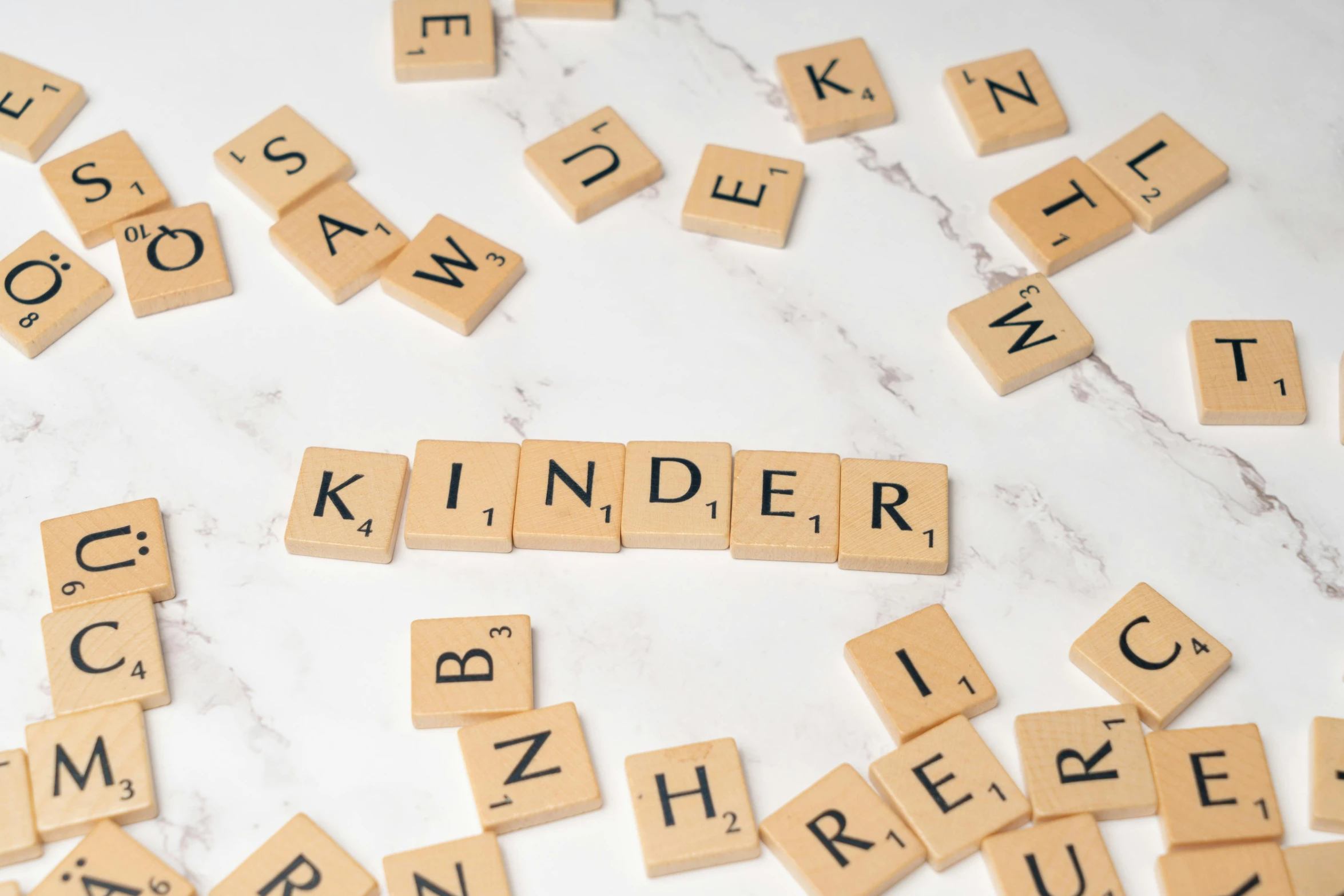 scrabbled word shapes and letters scattered around the word kinder