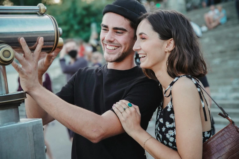 a couple looking through a telescope at the sight seeing people