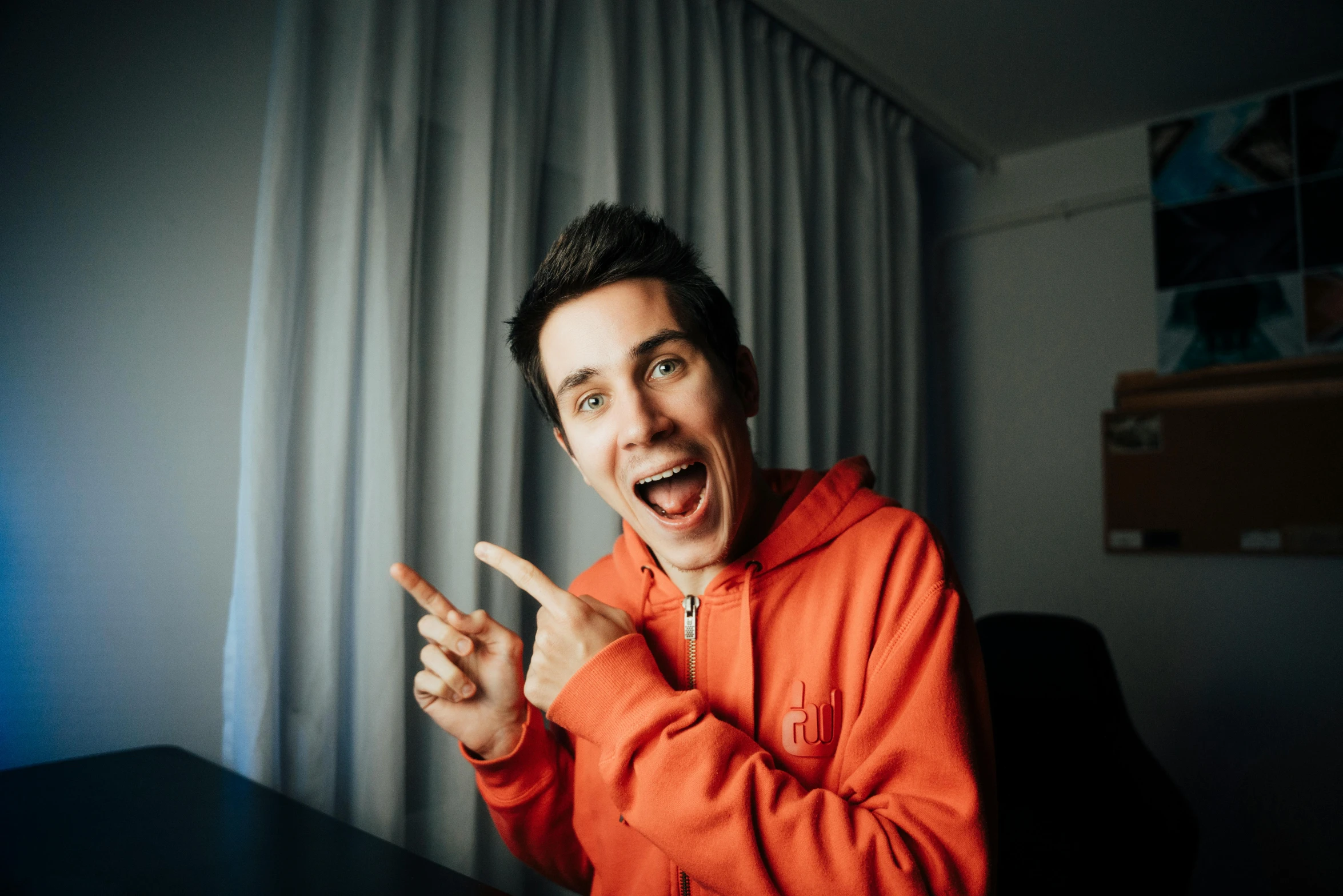 a man in an orange hoodie pointing at soing