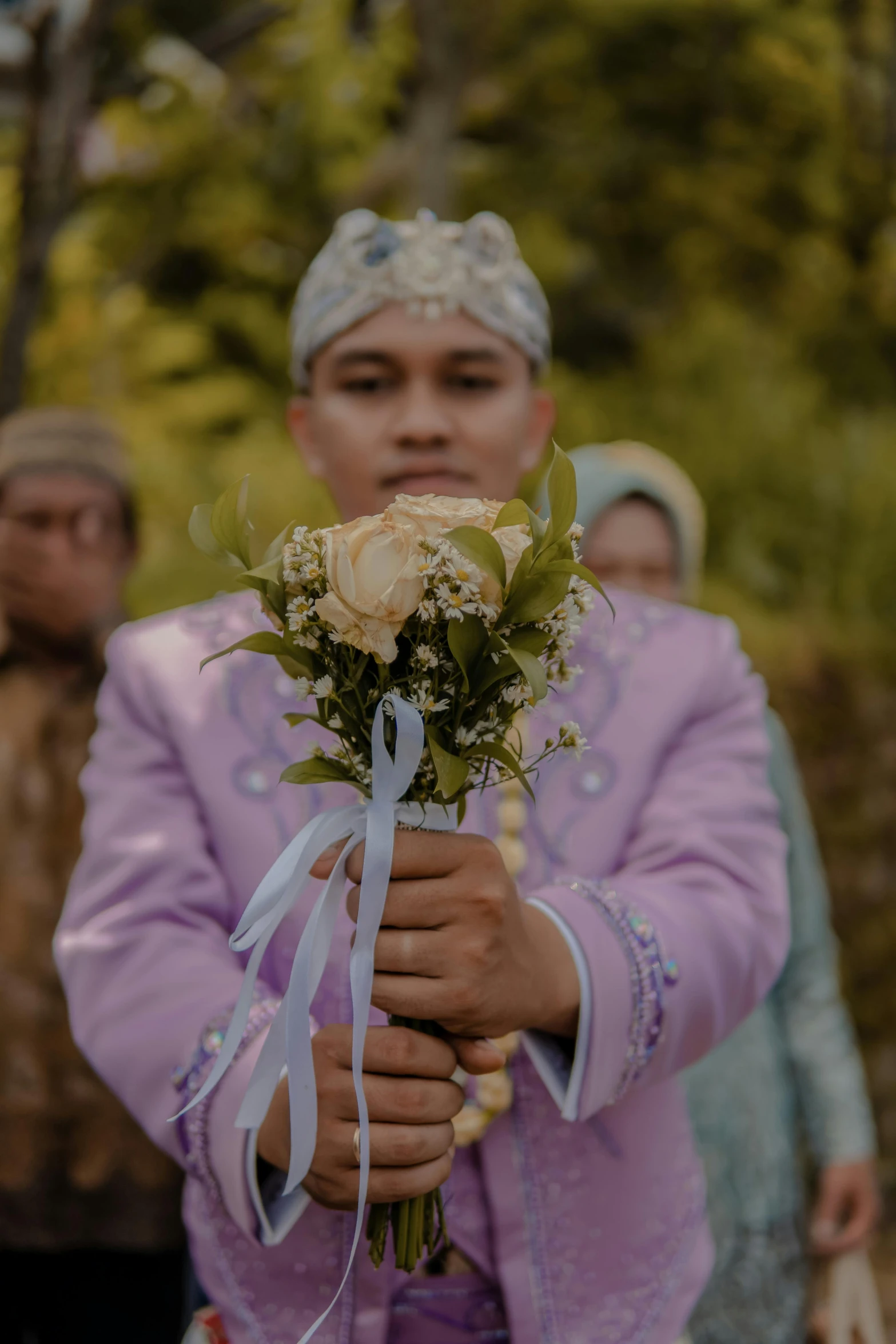 an individual wearing a pink suit holding a flower