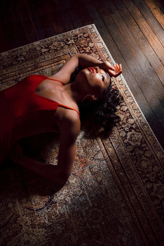 a woman in a red gown lies on a persian rug