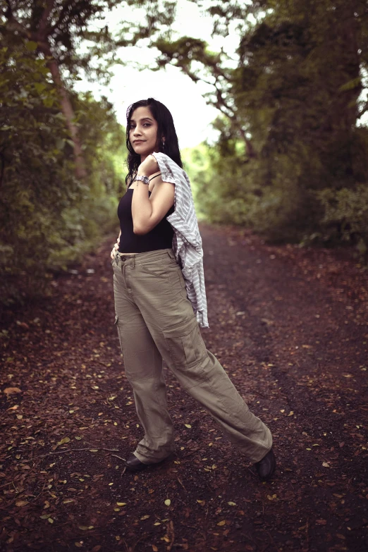 woman posing in middle of dirt road surrounded by trees