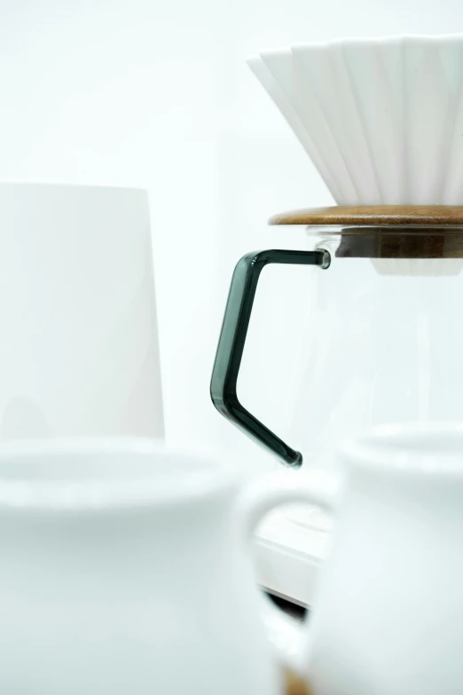 an empty white coffee pot with a black handle on it