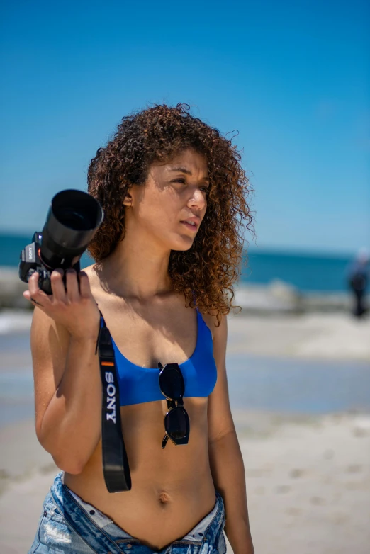 a woman with curly hair holding up a camera