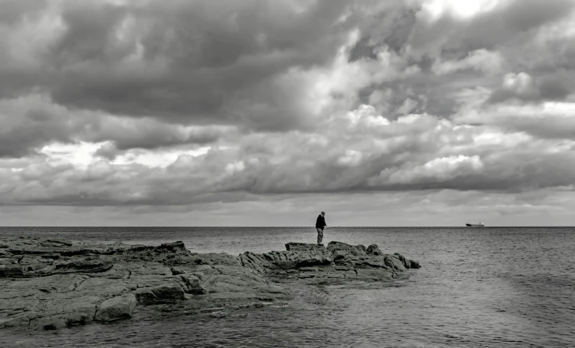 two people standing on rocks in the middle of a large body of water