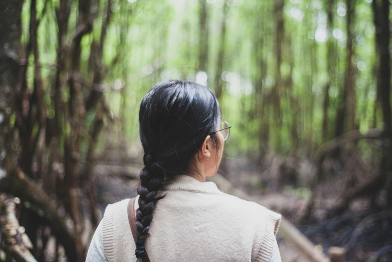 a woman standing in a forest with lots of trees