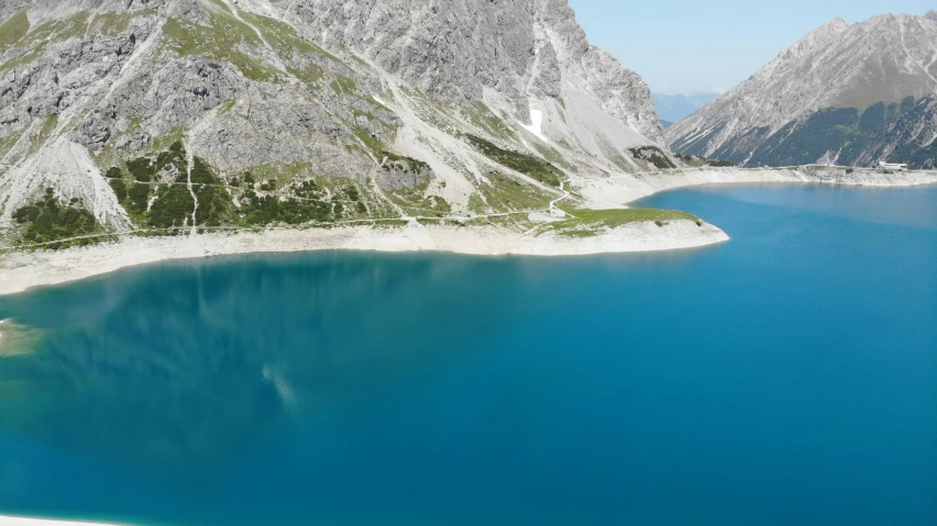 some mountains and blue water surrounded by green plants