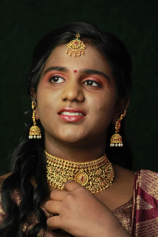 a woman in traditional indian jewelry with green background