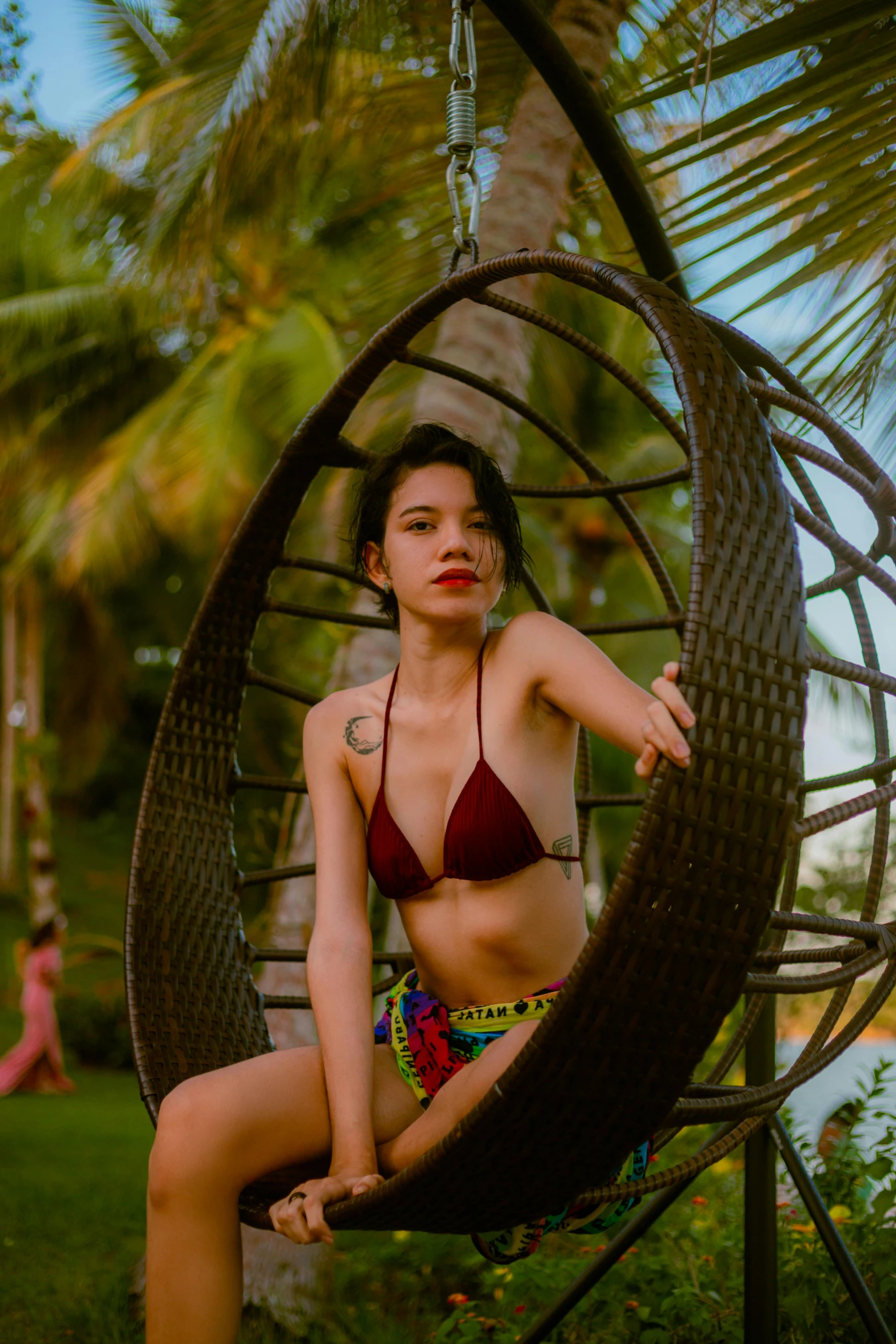 a girl wearing a red bikini is sitting on a swing