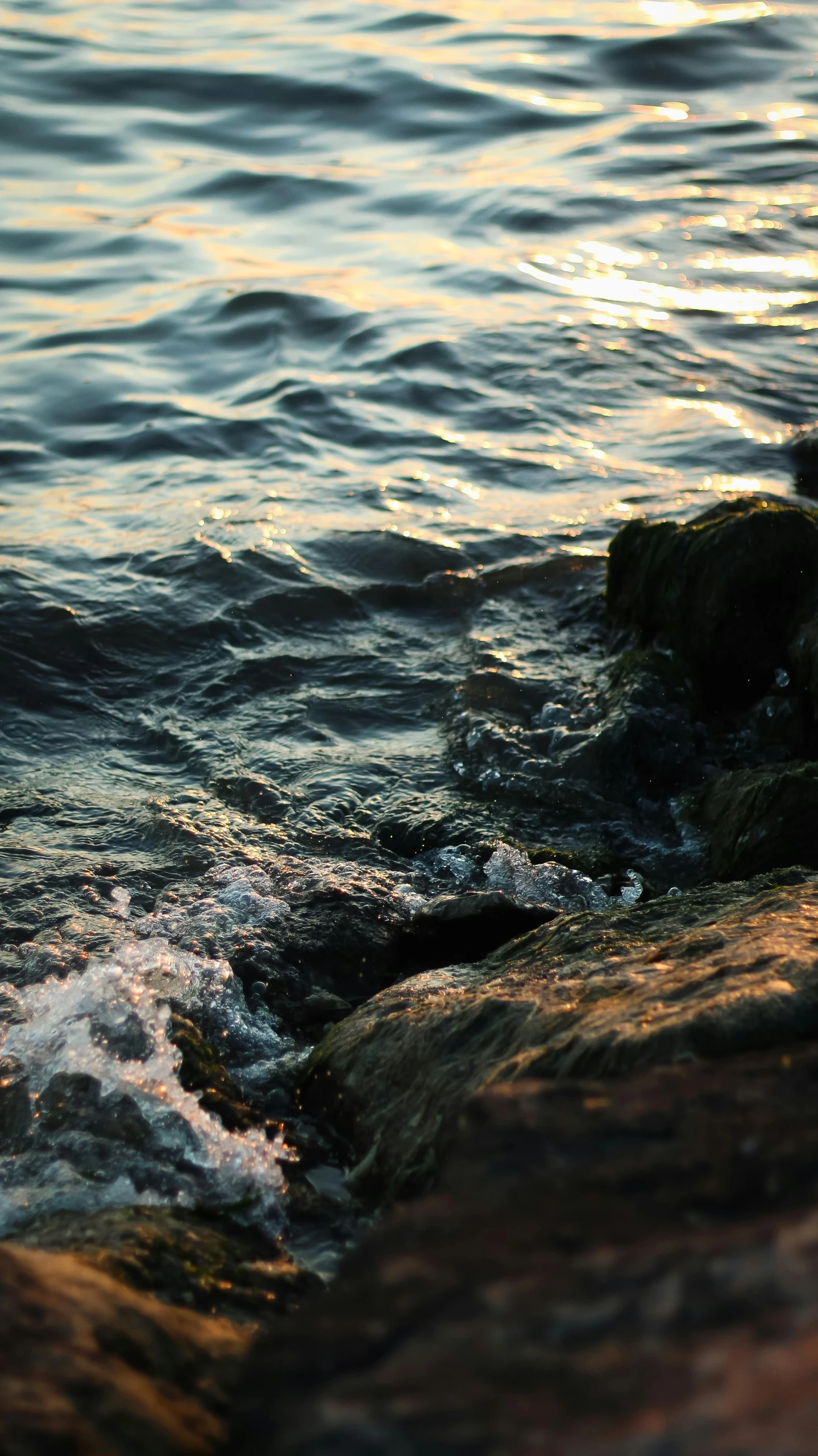 the sun shining on the water and rocks