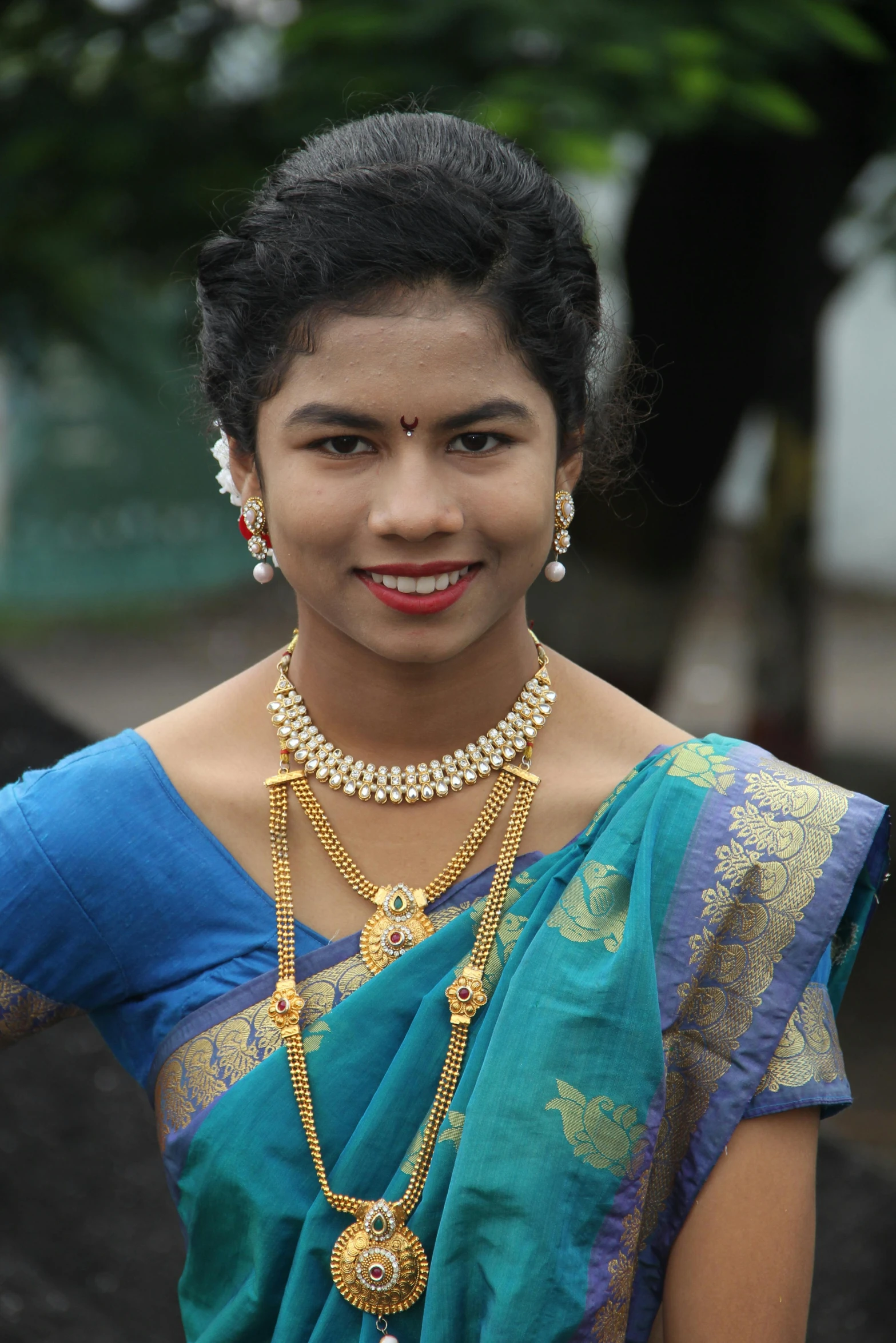 a woman wearing an ornate necklace and holding a large piece of gold jewelry