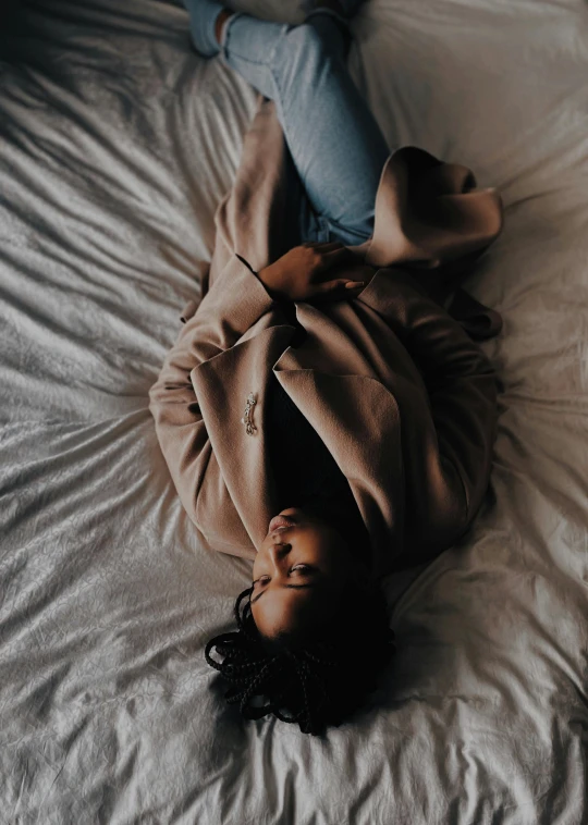 woman laying on bed with beige blanket next to feet