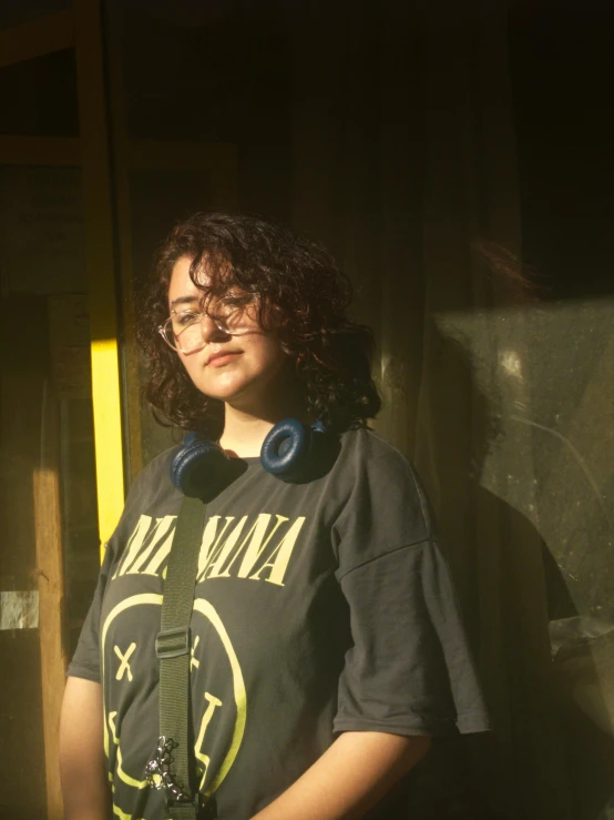 young female wearing earbuds standing in sun light