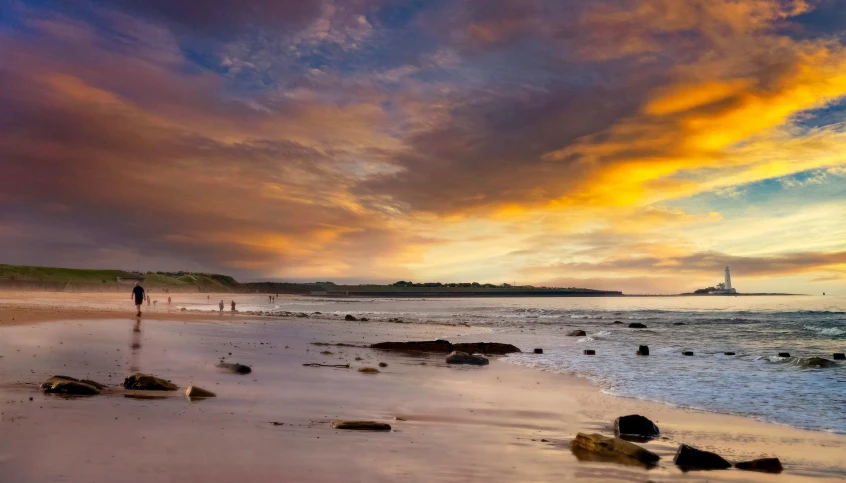 two people are walking on the beach near the water