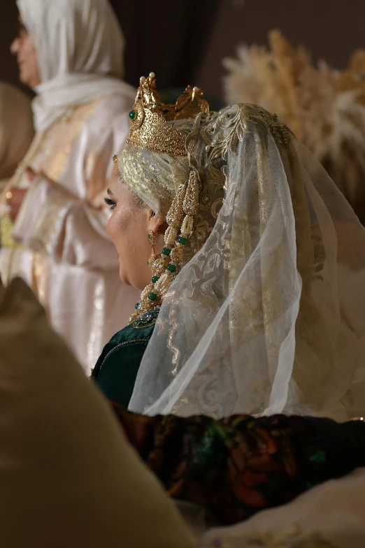 a woman in a veil and headdress looking at another women in a white dress